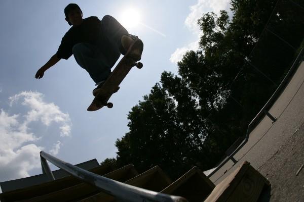 Silhouette of a skateboarder mid jump at a community skate park.