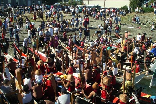 Sunny day on a Pacific coastal Washington beach where a gathering of tribal canoes and people are celebrating.