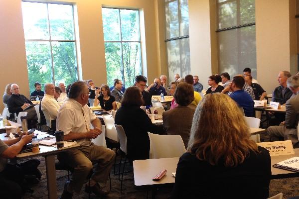 Large conference room full of interdepartmental officials in planning session.
