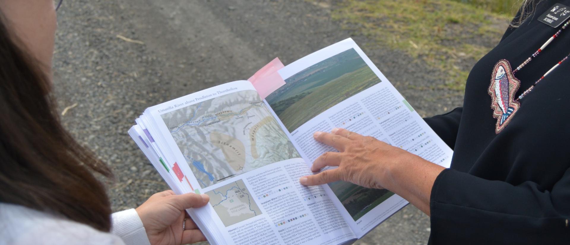 Tribal elder pointing at text in book about the Umatilla River.