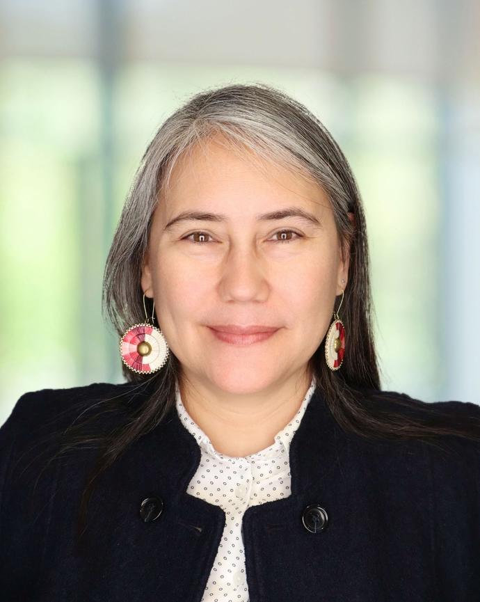 Woman in black blazer and white collared shirt, headshot only.